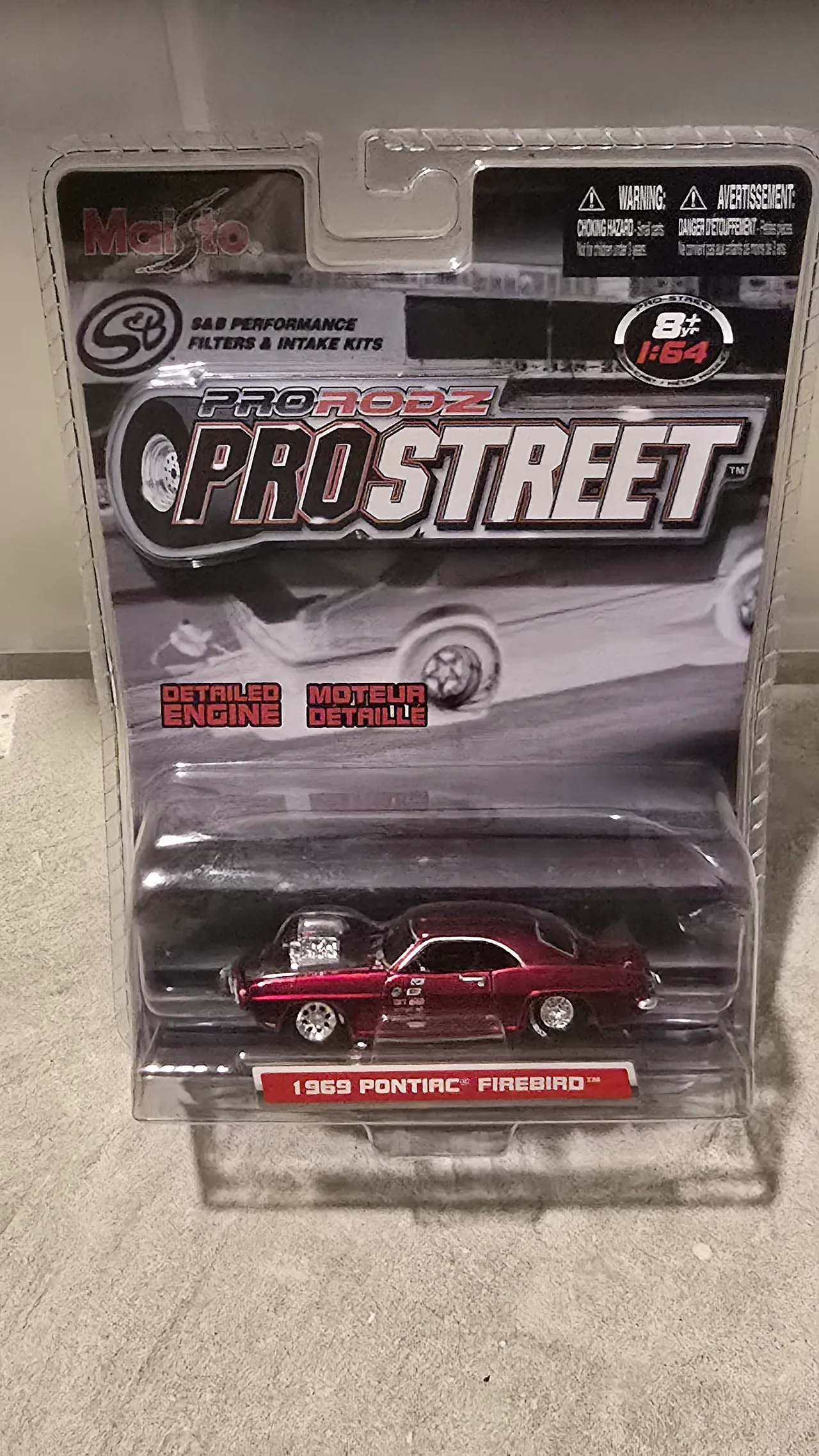 Candy red 1969 Pontiac Firebird drag car with a black roof and a blower by Maisto, Pro Rodz Pro Street, in its blister pack