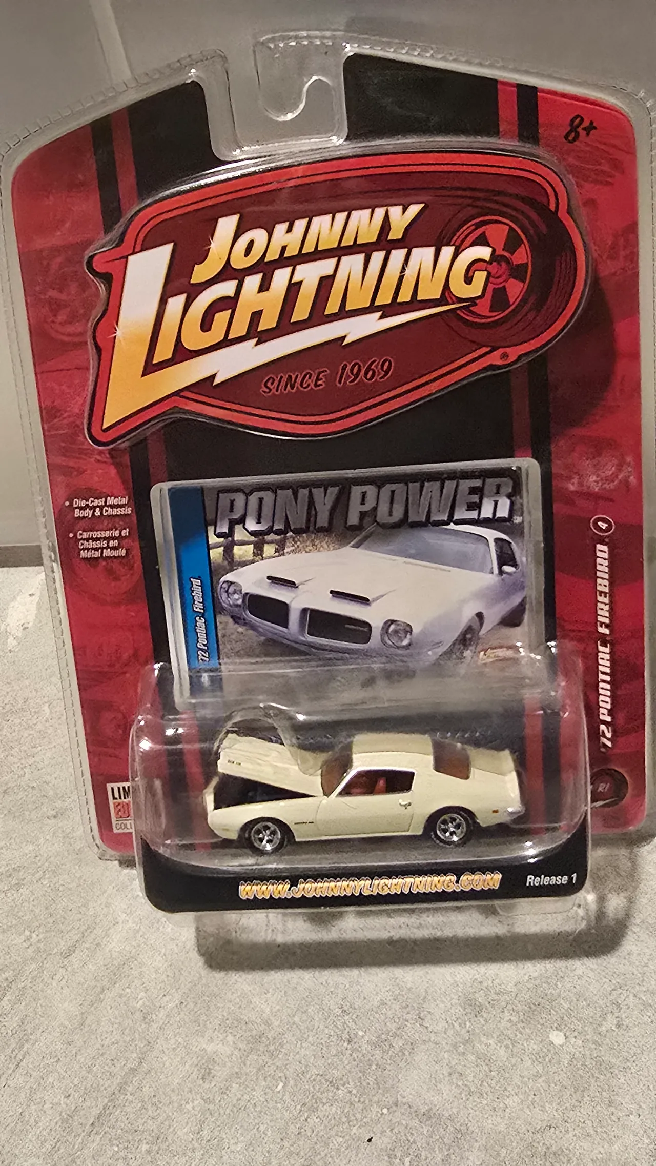 Cream 1972 Pontiac Firebird with its hood open by Johnny Lightning, Pony Power, in its blister pack