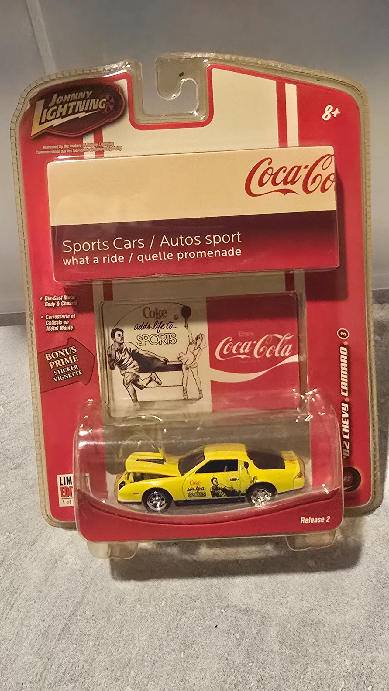 Yellow 1982 Chevy Camaro with a black roof and Coca-Cola graphics by Johnny Lightning, Coca-Cola Sports Cars, in its blister pack